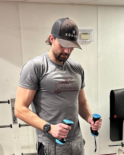 Man in gym holding a Kuhler in each and between reps in the gym.